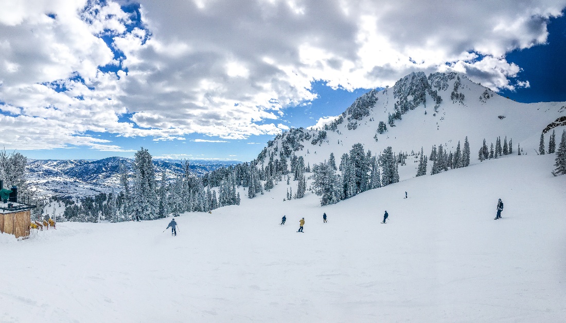 Skiers in Utah making their way down a snow-covered mountain slope.